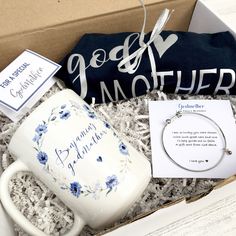 an open box containing a bracelet, coffee mug and necklace with a note on it