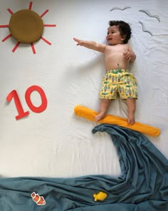 a young boy laying on top of a bed next to a wall with the number ten