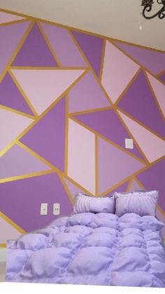 a purple and gold bedroom with a chandelier hanging from the ceiling above it