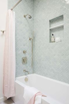 a white bath tub sitting next to a shower with a pink towel on top of it