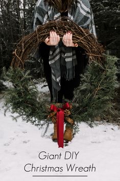 a woman standing in the snow holding a wreath