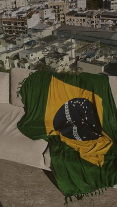 a green and yellow blanket sitting on top of a white couch in front of a cityscape