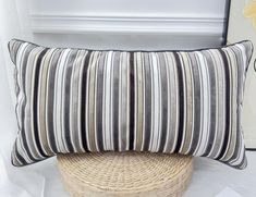 a striped pillow sitting on top of a wicker basket next to a white wall