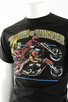 "Black double-sided graphic tee shirt. Front with Masters of Thunder # 1 series &2 motorcycle racers. Back of tee has Andrea's Harley Davidson Urbana, IL. 1992copyright date. Great pre-owned vintage, however, there is a hole in the left underarm about 1/2\" long. Vintage Tag Size: M 38-40 Material: cotton Closure: Pullover Chest: 38\" Length: 28\" -------------------------------------------------------------------------------- Gender: Men Modified Item: No Country/Region of Manufacture: Unit Vintage Short Sleeve T-shirt For Motorcycling, Racing Graphic Print T-shirt For Motorcycling, Retro Graphic Print T-shirt For Biker Events, Vintage Crew Neck T-shirt For Motorcycling, Racing Style Graphic Print T-shirt For Fans, Vintage Short Sleeve Motorcycling T-shirt, Vintage Short Sleeve Tops For Motorcycling, Motorcycle Racers, Mom Jeans Shorts