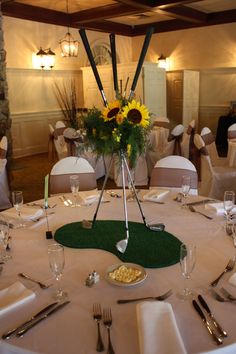 a golf themed table setting with sunflowers and silverware on the centerpiece