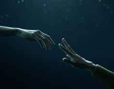 two hands reaching out towards each other in the dark blue water with sunlight shining on them