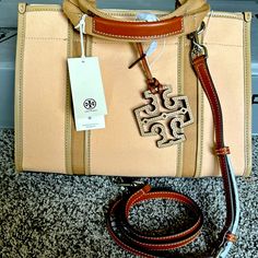 Brand New Tory Burch Tote. Never Worn, New With Tags. Height: 8.9" (22.5cm); Length: 12.4" (31.5cm); Depth: 3.9" (10cm) Cotton Canvas; Faux Leather And Calf Leather Trim, Silver Hardware, Center Snap Closure; Snaps On Gussets Webbing Top Handles With 3.9" (10cm) Drop; Adjustable, Removable Leather Crossbody Strap With 21.3" (54cm) Drop, 1 Exterior Front Slit Pocket, 1 Interior Back Wall Slit Pocket Leather Base Hanging Logo Charm Tory Burch Robinson Tote, Tory Burch Ella Tote, Ella Tote, Slouchy Tote, Tory Burch Tote, Tory Burch Bag Totes, Leather Handbags Tote, Tory Burch Bag, Small Tote