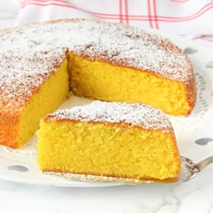 a cake that is sitting on a plate with a slice taken out of it and powdered sugar on top