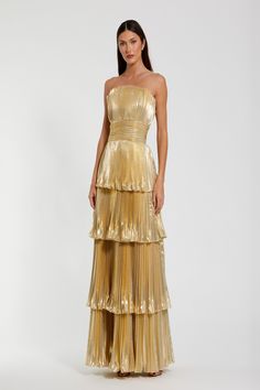 a woman is wearing a gold dress with tiered layers and a strapless top