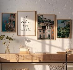 three framed pictures hang on the wall above a table with chairs and vases in front of it