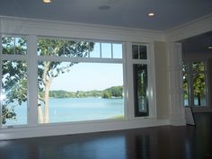 an empty room with large windows overlooking the water