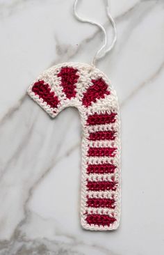 a crocheted white and red object on a marble surface with a string attached to it