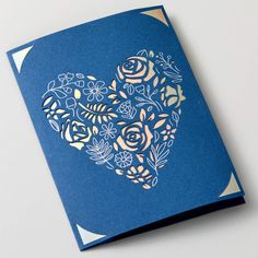 a blue greeting card with gold foil flowers and leaves in the shape of a heart