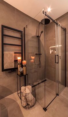 a bathroom with a stand up shower next to a candle holder and two towels on the floor