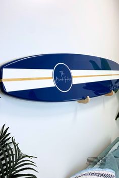 a blue and white surfboard hanging on the wall next to a potted plant