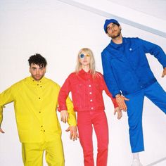 three people dressed in bright colored clothing standing next to each other