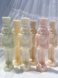 seven small ceramic figurines are lined up on a white tableclothed surface