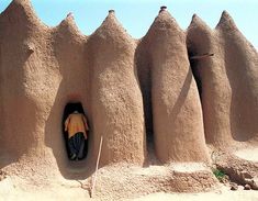 a man is standing in the entrance to a building made out of sand and rocks