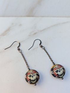 These one-of-a-kind earrings are made from vintage bottle caps, repurposed into unique round beads. The bottle caps are first made into domes, soldered together, and drilled to make round beads. Caps have been used, cleaned, and repurposed for jewelry.  Black Jack Pirate Ale Beads hang from a black gunmetal-plated chain with gunmetal-plated sloped ear wires. The base metal is brass, nickel-free, and lead-free. The ear wires are hammered with smooth ends and 21 gauge. They measure 25mm X 10mm. Stainless steel ear wires are available for an additional $5.00 fee. Please message me. Skeleton Jewelry, Earrings Halloween, Black Jack, Vintage Bottle, Vintage Beads, Jewelry Black, Halloween Skeleton, Bottle Caps, Skull And Crossbones