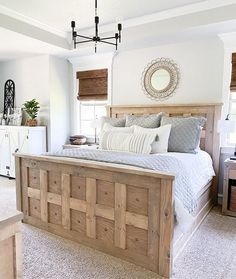 an instagramted photo of a bed in a bedroom with white walls and wooden headboard