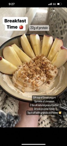 a bowl filled with oatmeal and apples on top of a table next to a person