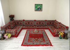 a living room filled with lots of red couches and rugs on the floor