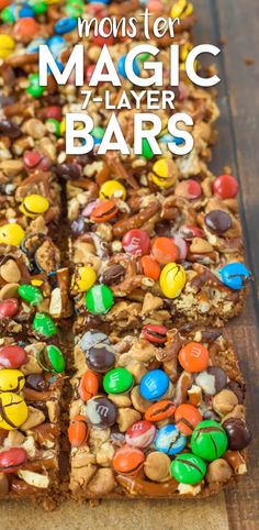 a close up of a slice of candy bar on a wooden table with the words monster magic layer bars