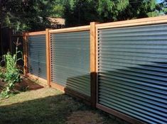 a fence that is made out of metal sheets and wood slats, in the backyard