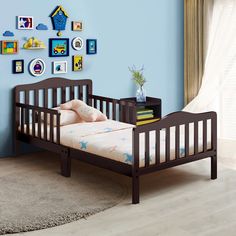 a small child's bed in a room with blue walls and pictures on the wall