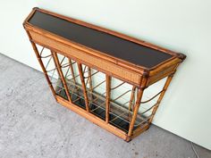 an old bamboo and glass display case on the floor in front of a white wall