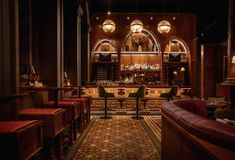 a dimly lit bar with red leather seats