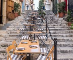 an outdoor dining area with tables and chairs on the steps leading up to some buildings