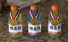 three bottles with medals on them sitting on a counter top next to a bottle of water