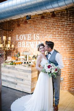 a bride and groom standing next to each other in front of a sign that says love is brew