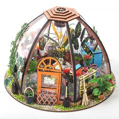 a glass dome filled with lots of different types of flowers and plants on display in front of a white background