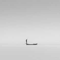 a man standing on top of a boat in the middle of a large body of water