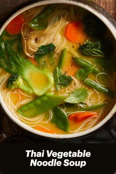 a bowl filled with noodles and vegetables on top of a wooden table