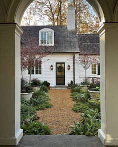 an archway leading to a white house surrounded by greenery