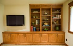 an entertainment center with bookshelves, television and vases