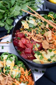 two black bowls filled with food and garnished with cilantro, avocado, carrots