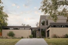 a modern house with large windows on the front and side walls, surrounded by grass and trees