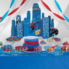 a spiderman themed birthday party with cake and cupcakes on a blue table