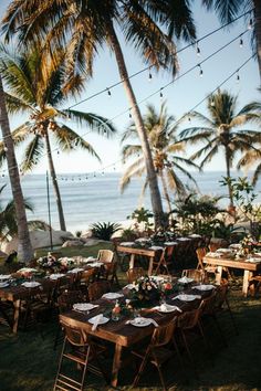 an outdoor dining area with tables and chairs set up on the grass by the beach