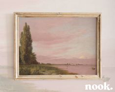 a painting hanging on the wall next to a white frame with an image of trees and water