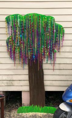 a tree with beads hanging from it's trunk in front of a white house