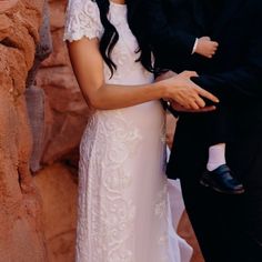 a man in a suit and tie holding a woman in a white dress with long hair