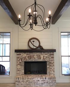 an image of a living room with a fire place and chandelier hanging from the ceiling