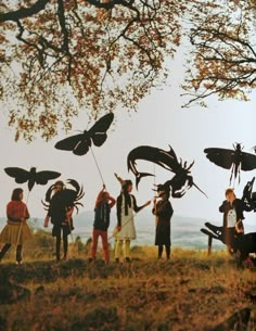 some people are standing in the grass with bugs on their heads and holding onto kites