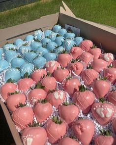 a box filled with lots of pink and blue chocolate covered strawberries next to each other