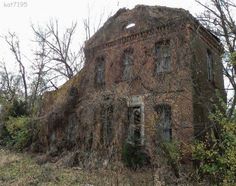 an old brick building with vines growing on it's side and windows in the front